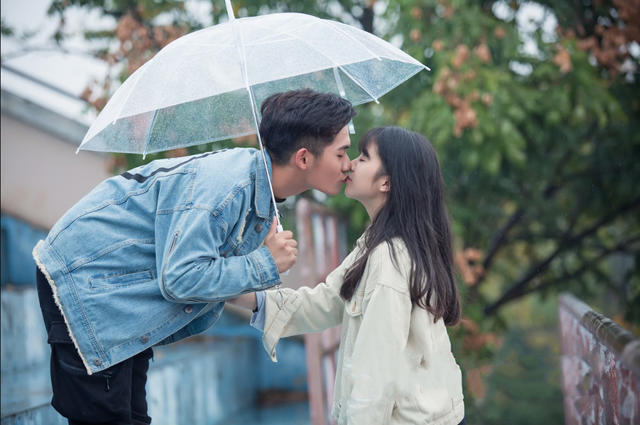 在雨中撑着伞亲吻的男女