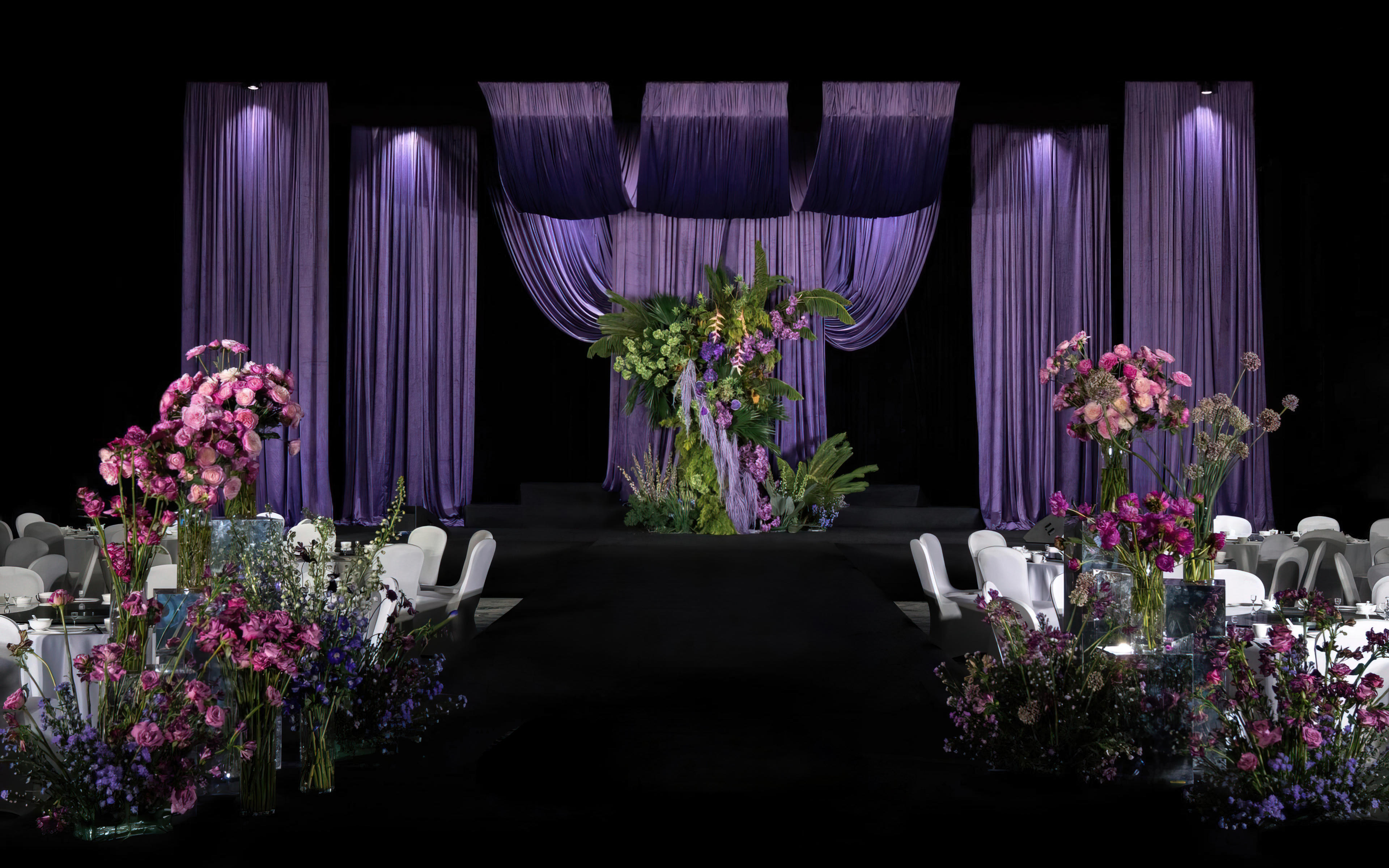 深紫帷幔垂落，粉紫花艺盛放