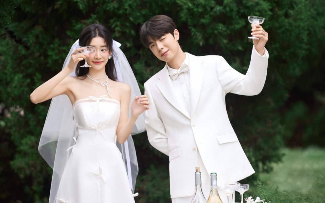 在綠意盎然的背景下，一對(duì)新人手牽手，笑容燦爛。