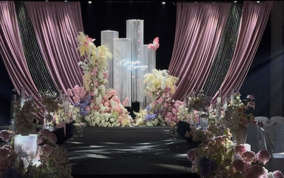 豆沙色布幔映襯粉玫瑰，流蘇輕垂，光束燈暈染柔光